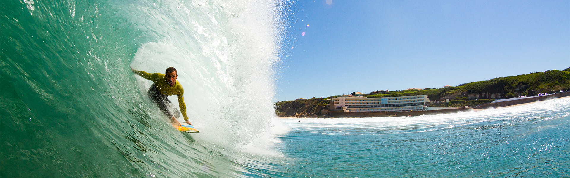 Surfer riding a wave at Praia Grande with the coastline behind
